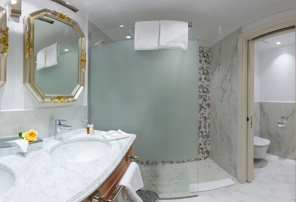 Elegantes Badezimmer mit marmorierten Wänden, zwei Waschbecken und einem modernen Duschbereich. Große Spiegel reflektieren das Licht, während frische Handtücher und eine Blume auf dem Waschbecken f... Hotel mit Appartements für Familien, Kroatien - am Meer