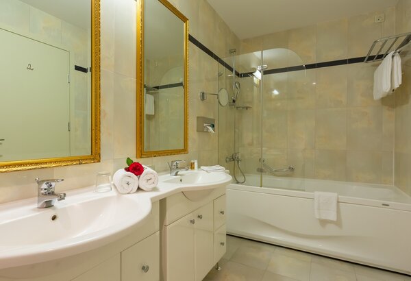 Elegantes Badezimmer mit zwei Waschbecken, großen Spiegeln und einer Badewanne. Die Wände sind in sanften Farbtönen gehalten, und frische Handtücher sowie eine kleine Blumendekoration verleihen dem... Appartements für Familienurlaub Crikvenica, Kroatien