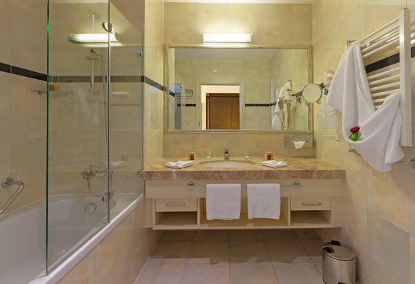 Modernes Badezimmer mit Badewanne und Dusche, großen Spiegeln und eleganten Armaturen. Helle Fliesen und eine warme Farbpalette schaffen eine einladende Atmosphäre. Handtücher sind ordentlich auf d... Meerblick Hotel Kroatien - Ihr Komfort Doppelzimmer